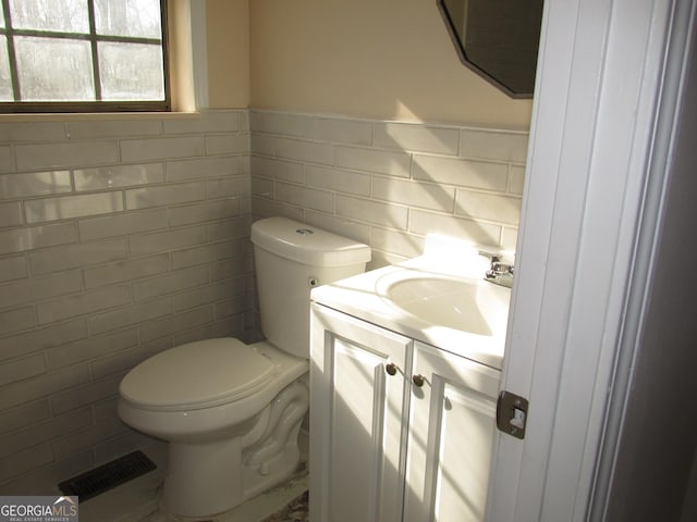 bathroom featuring tile walls, vanity, and toilet