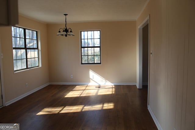 unfurnished dining area with dark wood-type flooring, an inviting chandelier, and ornamental molding