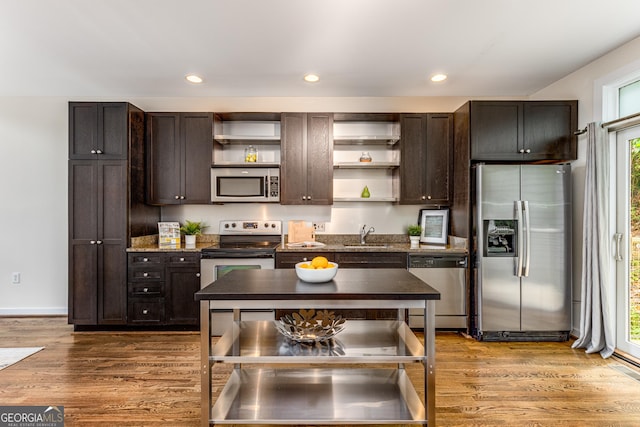 kitchen with sink, appliances with stainless steel finishes, dark brown cabinetry, and hardwood / wood-style floors