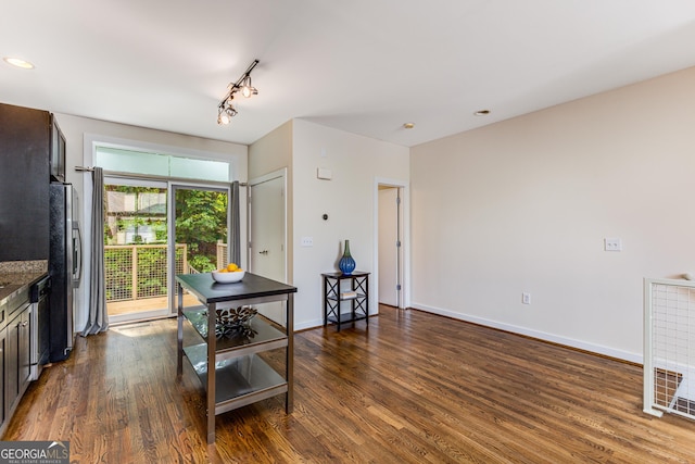 kitchen featuring stainless steel appliances, track lighting, and dark wood-type flooring