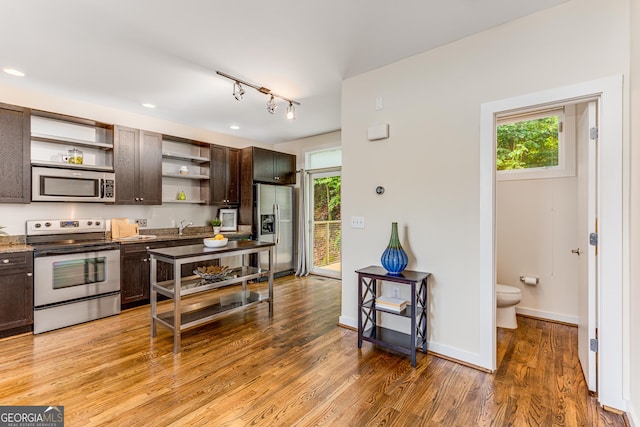 kitchen with a healthy amount of sunlight, dark brown cabinets, stainless steel appliances, and wood-type flooring