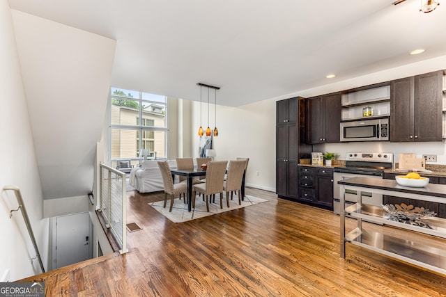 kitchen featuring dark brown cabinetry, hanging light fixtures, a wall of windows, dark hardwood / wood-style floors, and appliances with stainless steel finishes