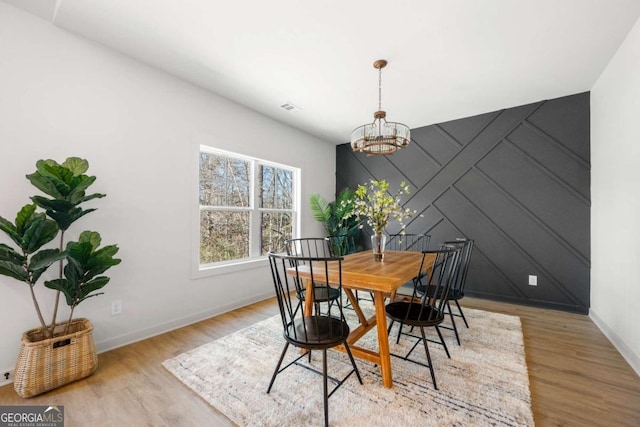 dining space with light wood-type flooring and an inviting chandelier