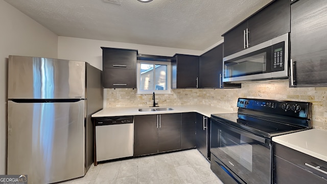 kitchen featuring a textured ceiling, backsplash, sink, and appliances with stainless steel finishes