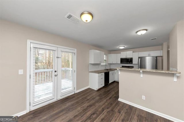 kitchen featuring french doors, stainless steel appliances, tasteful backsplash, a kitchen breakfast bar, and white cabinets