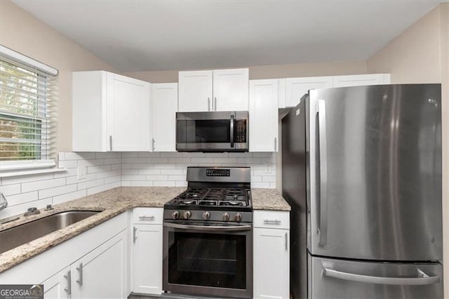 kitchen featuring decorative backsplash, stainless steel appliances, and white cabinetry