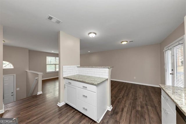 kitchen featuring dark wood-type flooring, white cabinets, decorative backsplash, light stone counters, and kitchen peninsula