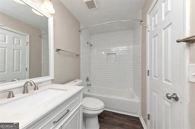 full bathroom featuring tiled shower / bath, vanity, wood-type flooring, and toilet