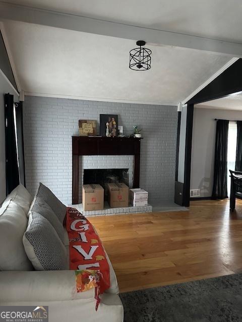 living room with hardwood / wood-style floors, a fireplace, and brick wall