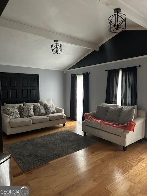 living room with vaulted ceiling with beams, wood-type flooring, and an inviting chandelier