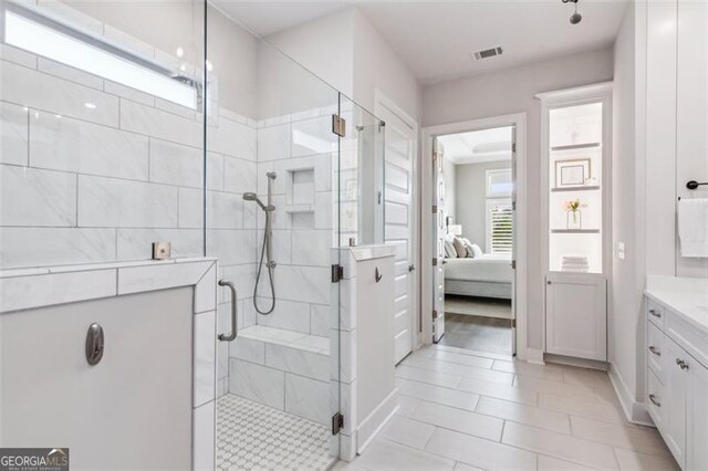 bathroom featuring a shower with shower door, tile patterned floors, vanity, and a chandelier