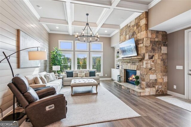 living room featuring crown molding, dark wood-type flooring, a stone fireplace, coffered ceiling, and beamed ceiling