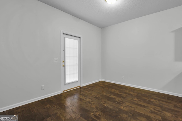 spare room with a textured ceiling, dark hardwood / wood-style floors, and vaulted ceiling