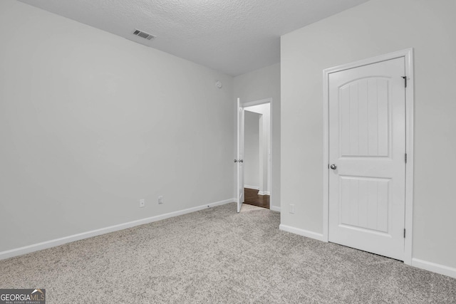 unfurnished bedroom with a textured ceiling and light carpet