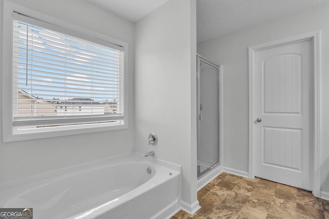 bathroom featuring shower with separate bathtub and a textured ceiling