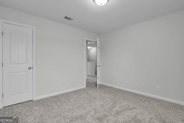 unfurnished bedroom featuring a textured ceiling and light carpet