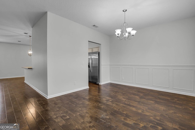 empty room featuring dark wood-type flooring and a notable chandelier