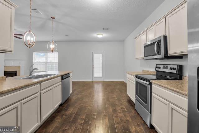 kitchen featuring pendant lighting, dark wood-type flooring, sink, a textured ceiling, and stainless steel appliances