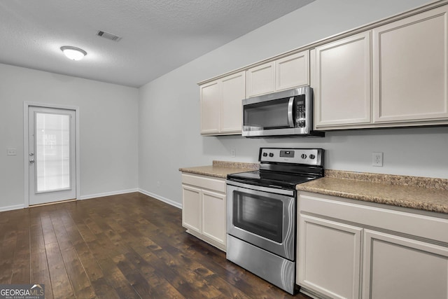 kitchen with a textured ceiling, stainless steel appliances, and dark hardwood / wood-style floors