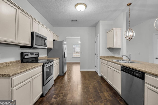 kitchen with sink, dark hardwood / wood-style floors, a textured ceiling, decorative light fixtures, and stainless steel appliances