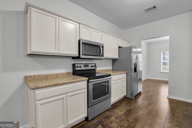 kitchen featuring white cabinets, appliances with stainless steel finishes, a textured ceiling, and dark wood-type flooring