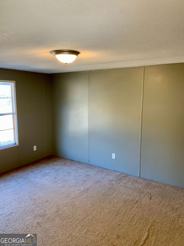 carpeted empty room featuring a textured ceiling