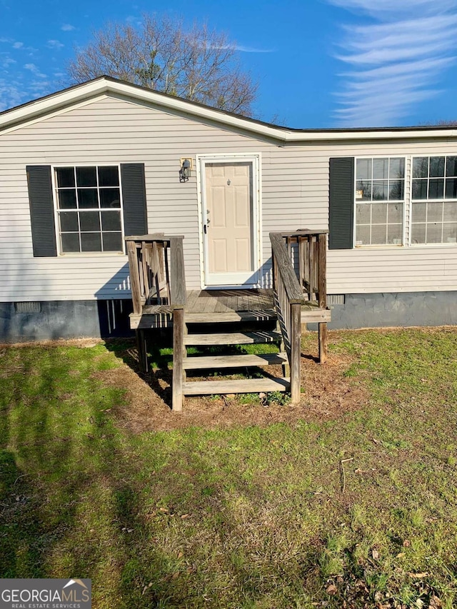 doorway to property with a lawn and a deck