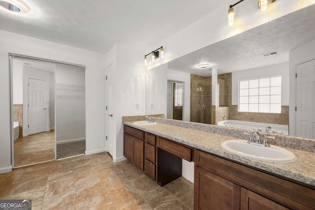 bathroom featuring a textured ceiling, vanity, and shower with separate bathtub