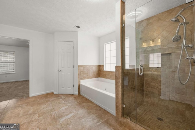 bathroom featuring a textured ceiling and independent shower and bath