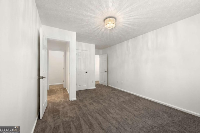 unfurnished bedroom with a textured ceiling and dark carpet