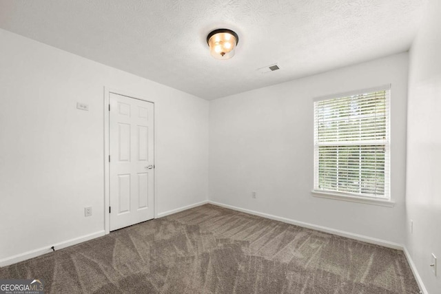 carpeted spare room featuring a textured ceiling