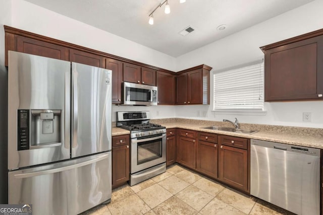 kitchen with light stone countertops, light tile patterned floors, sink, and appliances with stainless steel finishes