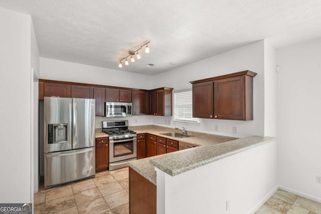 kitchen with kitchen peninsula, appliances with stainless steel finishes, track lighting, a textured ceiling, and sink