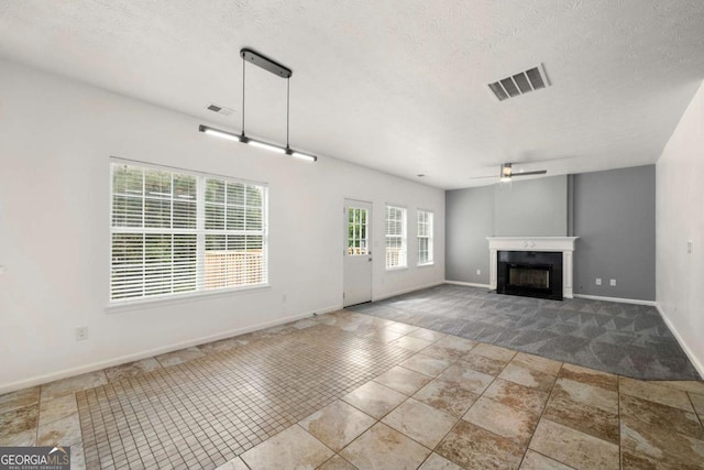 unfurnished living room featuring ceiling fan and a textured ceiling