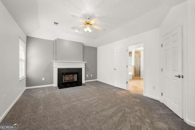 unfurnished living room featuring a tile fireplace, ceiling fan, and dark carpet