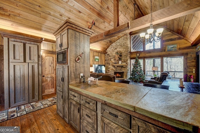 kitchen featuring an inviting chandelier, wood walls, dark hardwood / wood-style flooring, a fireplace, and beam ceiling