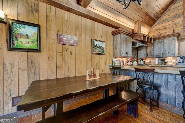 dining space featuring hardwood / wood-style flooring, wood walls, wood ceiling, and vaulted ceiling