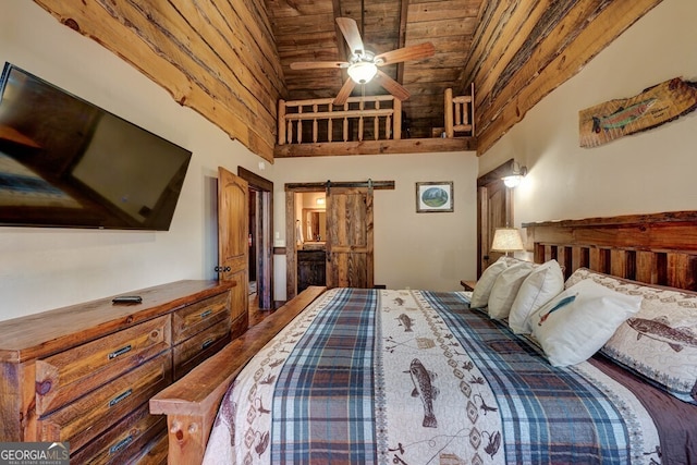 bedroom with wood ceiling, a barn door, hardwood / wood-style flooring, ceiling fan, and a towering ceiling