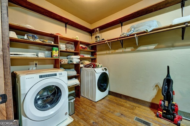 clothes washing area with separate washer and dryer and light hardwood / wood-style floors