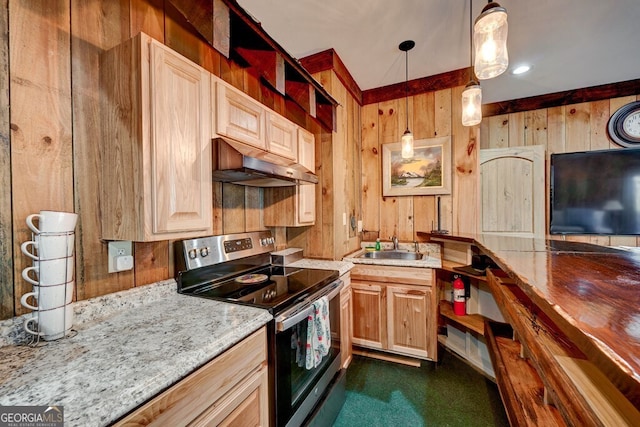 kitchen featuring stainless steel range with electric stovetop, wooden walls, decorative light fixtures, light stone counters, and sink