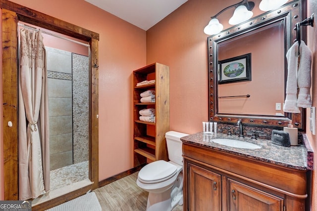 bathroom with wood-type flooring, toilet, walk in shower, and vanity