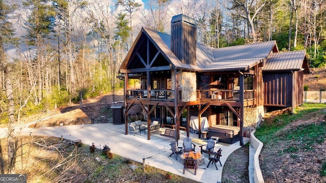 rear view of house featuring a wooden deck, a hot tub, a patio area, and a fire pit