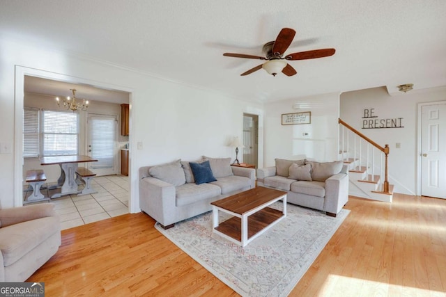 living room featuring hardwood / wood-style floors, ceiling fan with notable chandelier, and a textured ceiling