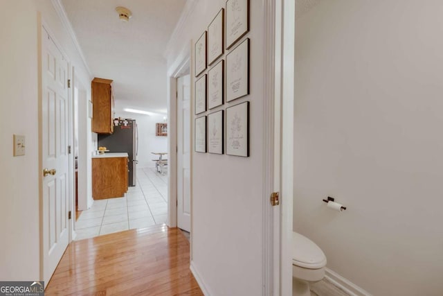 hall with light hardwood / wood-style flooring and ornamental molding