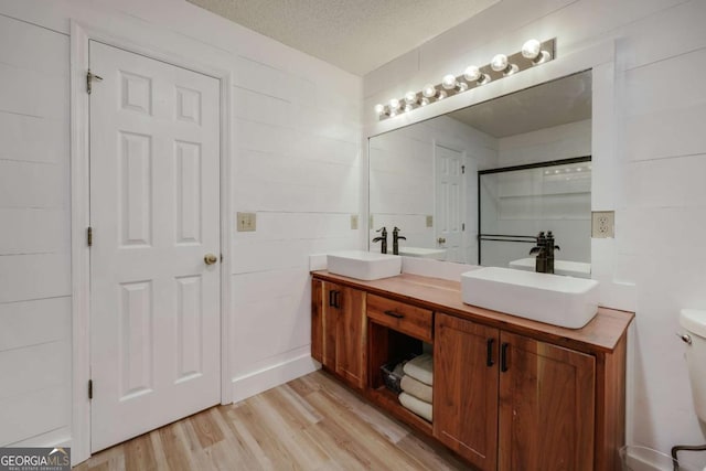 bathroom featuring vanity, wood-type flooring, a textured ceiling, and toilet