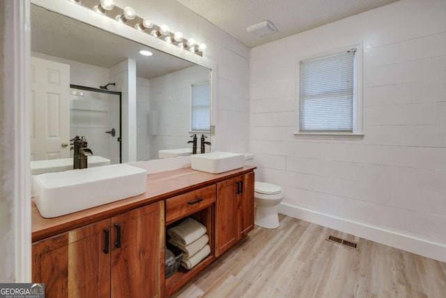 bathroom with vanity, a shower with shower door, toilet, a textured ceiling, and wood-type flooring