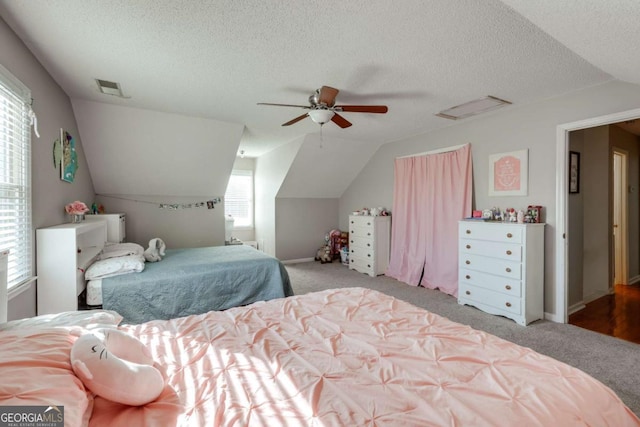 carpeted bedroom featuring a textured ceiling, vaulted ceiling, and ceiling fan