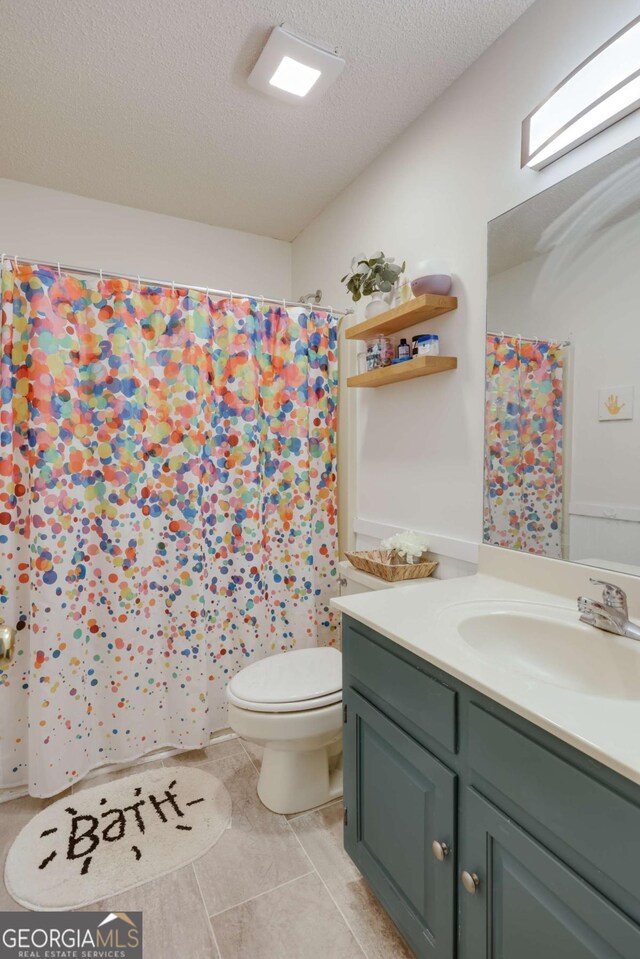 bathroom featuring tile patterned floors, vanity, toilet, and a textured ceiling