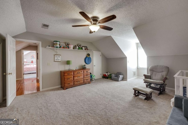 sitting room featuring ceiling fan, lofted ceiling, a textured ceiling, and carpet floors