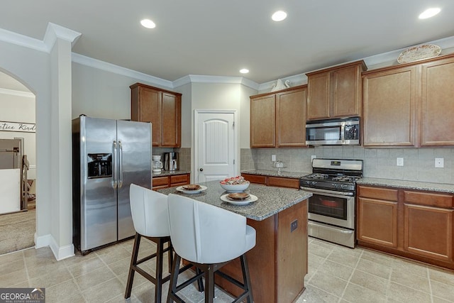 kitchen featuring appliances with stainless steel finishes, tasteful backsplash, a kitchen island, and light stone counters